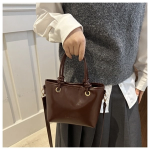Détail du sac à main vintage marron foncé avec texte gaufré et accents en métal doré