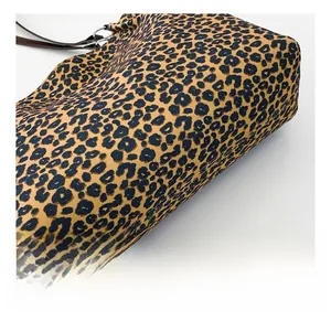 Detailed close-up showing the soft leopard print canvas texture and brown leather strap