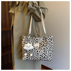 Detail of leopard print canvas bucket bag with cute white cloud plush charm on strap