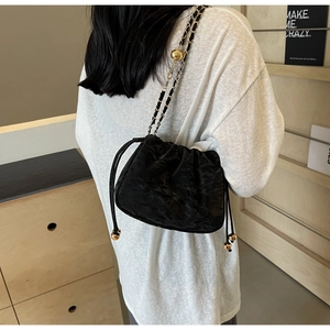Gros plan du sac nuage plissé avec chaîne dorée porté par un mannequin à l'épaule
