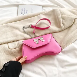 Detailed shot of pink leather handbag with silver bow clasp and chain strap