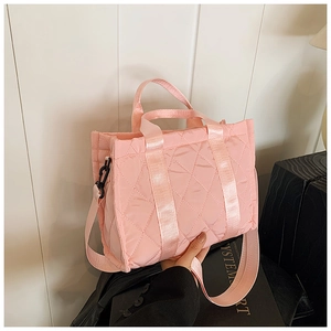 Close-up of pink quilted nylon tote bag with wide crossbody strap and metal carbine detail