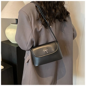 Détail du sac bandoulière en cuir noir avec un nœud en métal argenté sur le dos