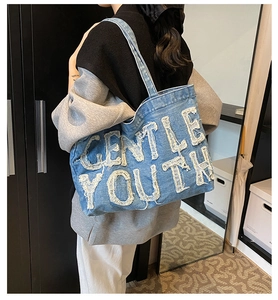 Détail du sac cabas en jean avec écusson Gentle Youth effiloché et texture vintage