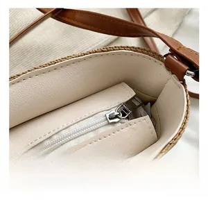 Detail shot of a woven straw beach bag featuring a silver zipper and durable brown strap