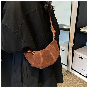 Dettaglio borsa a mezzaluna in camoscio marrone vintage con cuciture e tracolla annodata
