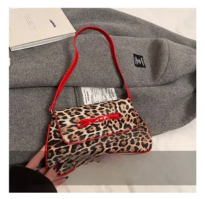 Detail of leopard print handbag featuring a red patent leather bow and shoulder strap