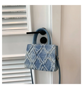 Close-up of blue denim tote bag with quilted frayed edge texture on a wooden background