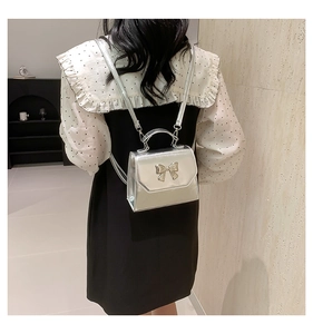 Silver metallic mini backpack with bow detail worn by model showing size and scale
