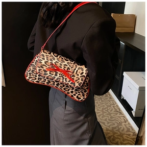 Detail of leopard print shoulder bag with red bow accent and edge trim on a model