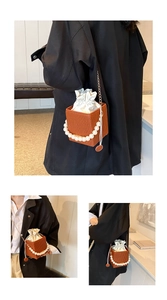 Close-up of brown bucket bag with pearl handle, chain strap and satin drawstring inner