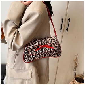 Leopard print faux fur baguette bag with red patent bow detail shown on a model