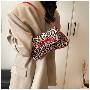 Detail of leopard print shoulder bag featuring a red 3D bow and vegan leather trim