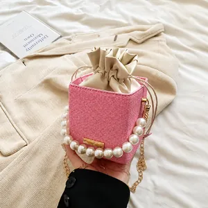 Détail du sac seau tissé rose avec poignée en perles, cordon de serrage et métal doré