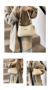 Detail of beige woven hobo bag with knotted rope strap and gold metal accent