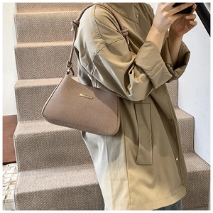 Detail of khaki shoulder bag with woven texture, knot strap, and gold metal bar
