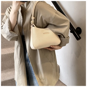 Detail of a beige woven hobo bag featuring thick rope handles and rectangular metal logo