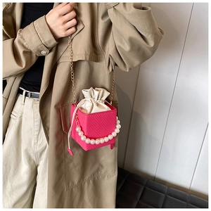 Detail einer pinkfarbenen Perlen-Würfeltasche mit Steppmuster und Goldkette