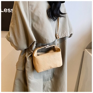 Vue détaillée du sac beige à texture tressée avec fermoir métallique sur le rabat