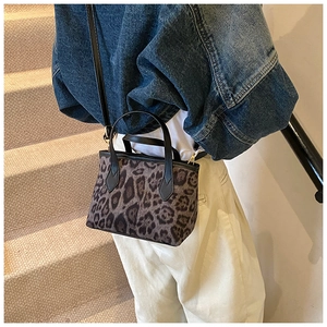 Dettaglio borsa a secchiello leopardata con manico in pelle nera e ganci metallici oro