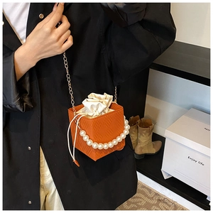 Detail der orangefarbenen Tasche mit Webstruktur, Perlengriff und Goldkette