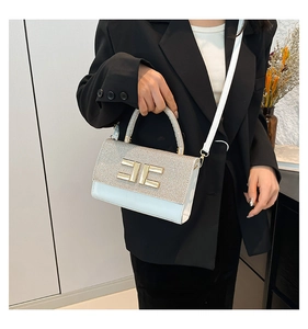 Detalle del bolso de cuero blanco con solapa de purpurina plateada y logo de metal dorado