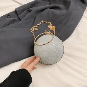 Macro shot of silver glitter spherical evening bag with golden ring handle and metal chain