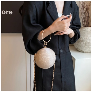 Macro detail of champagne glitter spherical evening bag with golden ring handle and chain