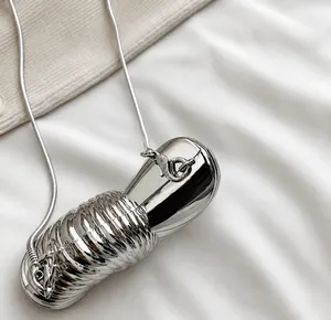 Detail of silver metallic mini bag showing spiral texture and lobster clasp on chain