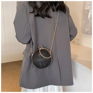 Close-up of black glitter spherical evening bag with gold ring handles and chain strap