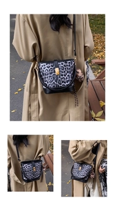 Detail of leopard print bucket bag with black leather base and plush charm on a model
