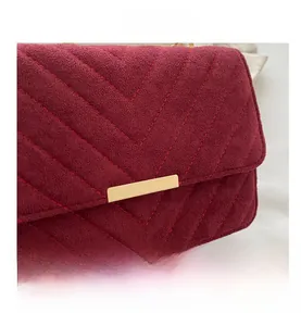 Macro shot of burgundy chevron quilted faux suede with a vintage gold rectangular clasp