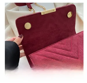 Detailed macro view of the gold magnetic buckle and V-shaped stitching on a burgundy bag