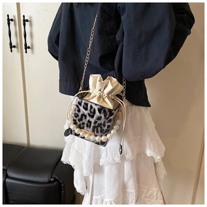 Detail of leopard print bucket bag featuring pearl handle and drawstring closure