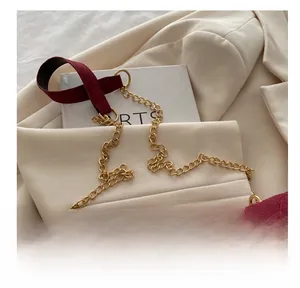 Detail of burgundy velvet and gold metal chain shoulder strap on a chic handbag