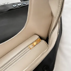 Detail view of the smooth golden metal zipper and premium white leather texture on the bag