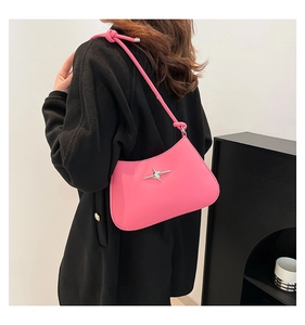 Bolso de hombro rosa con detalle de estrella plateada en modelo en estudio moderno