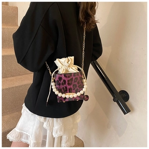Close-up of leopard print mini bag with pearl handle and golden chain crossbody strap