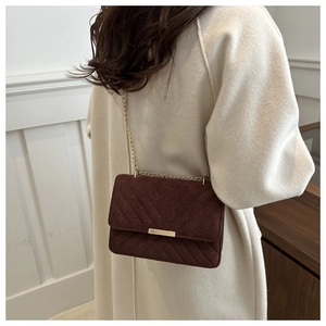 Detail of vintage brown suede crossbody bag with V-shaped quilting and gold chain strap