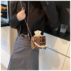 Detailed view of leopard print bucket bag with large pearl handle and chain strap