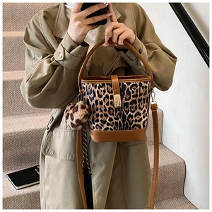 Leoparden-Eimertasche mit braunem Lederbesatz und Plüsch-Charm in einer Straßenszene