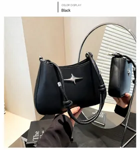 Detalle de bolso de cuero negro con adorno de estrella plateada y asa redonda
