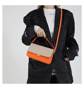 Detalle de un bolso cuadrado en patchwork naranja y beige con un cierre dorado redondo