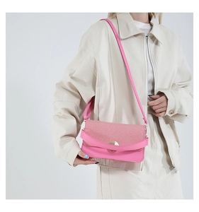 Bolso bandolera rosa fucsia combinado con un conjunto crema de estilo moderno