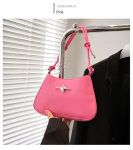 Detalle de bolso rosa con adorno de estrella plateada colgado en percha metálica