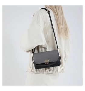Detalle del bolso bandolera con solapa gris texturizada y hebilla redonda de metal dorado