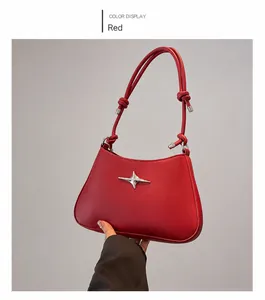 Detalle de bolso de hombro en cuero rojo con estrella plateada y diseño de nudo