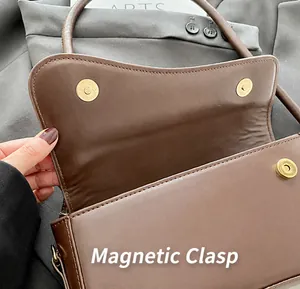 Dettaglio della borsa in pelle marrone con chiusura a scatto magnetica in metallo dorato