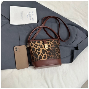 Close-up of leopard print bucket bag with brown leather straps and gold twist-lock detail