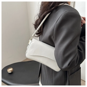 Vista lateral de bolso de hombro blanco minimalista con solapa llevado por modelo en estilo